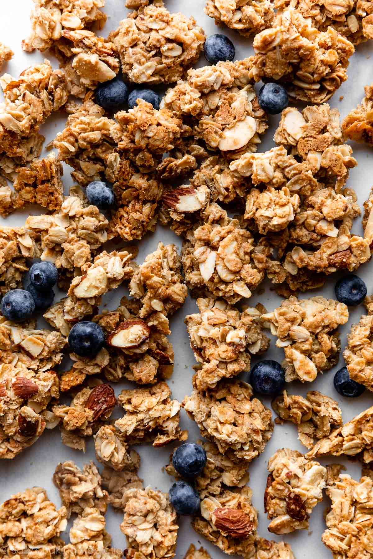 clusters of maple almond granola spread out with blueberries dotted all over.