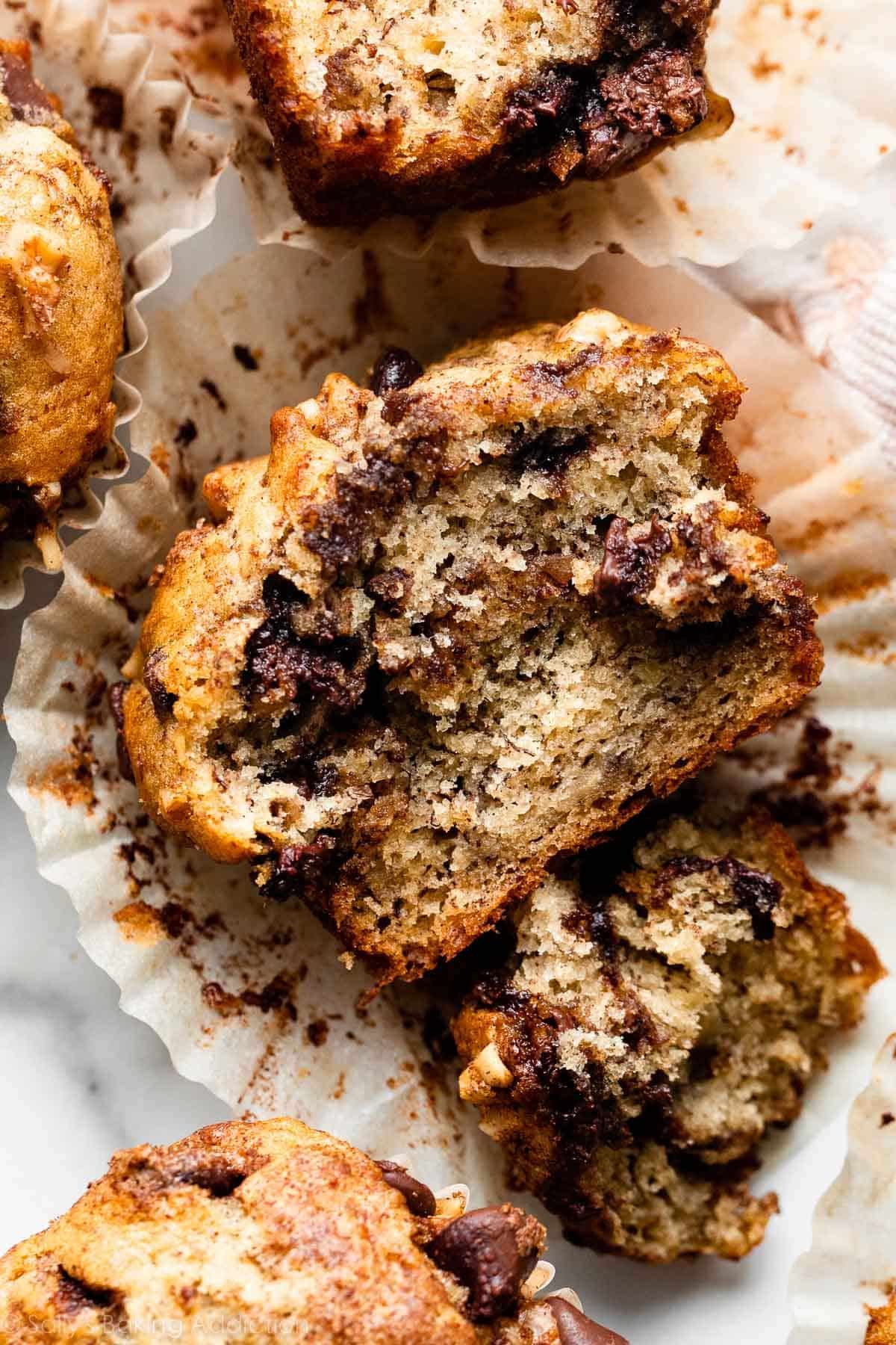 banana chocolate chip cinnamon streusel muffin cut open sitting in muffin wrapper.