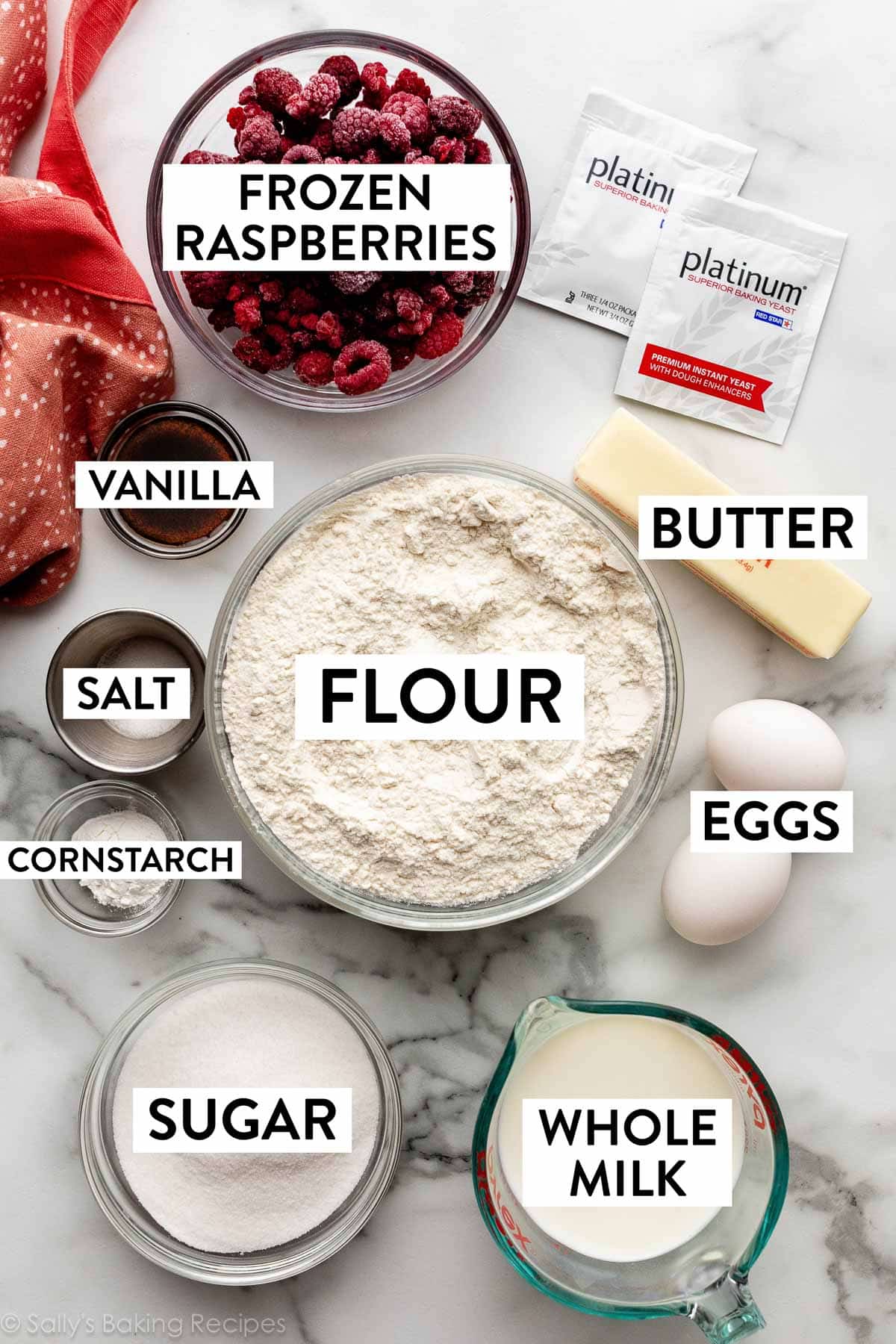 ingredients on counter including flour, butter, yeast packets, salt, whole milk, sugar, and eggs.