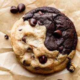 close-up photo of a chocolate and peanut butter swirl cookie on brown parchment paper.