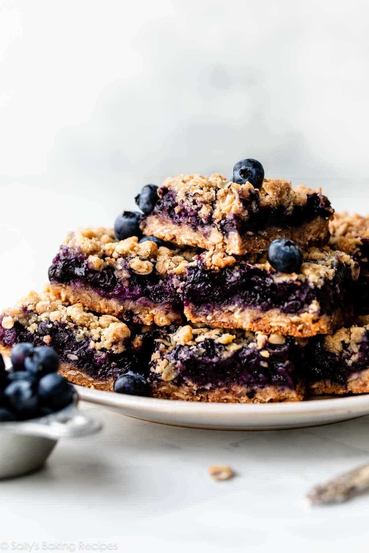 plate of blueberry pie bars with fresh blueberries dotted on top.