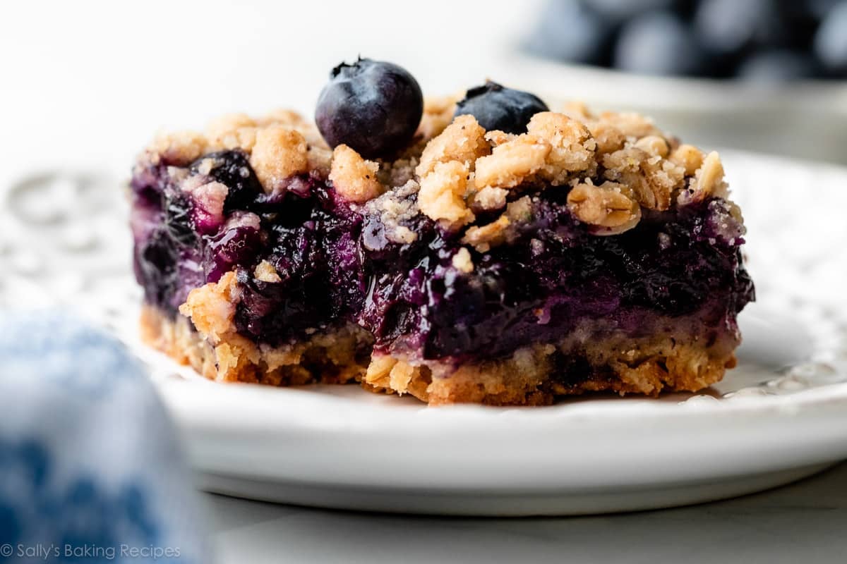 blueberry pie bar with bite taken out on white plate.