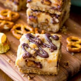 peanut butter cup pretzel cheesecake bars on a wood board