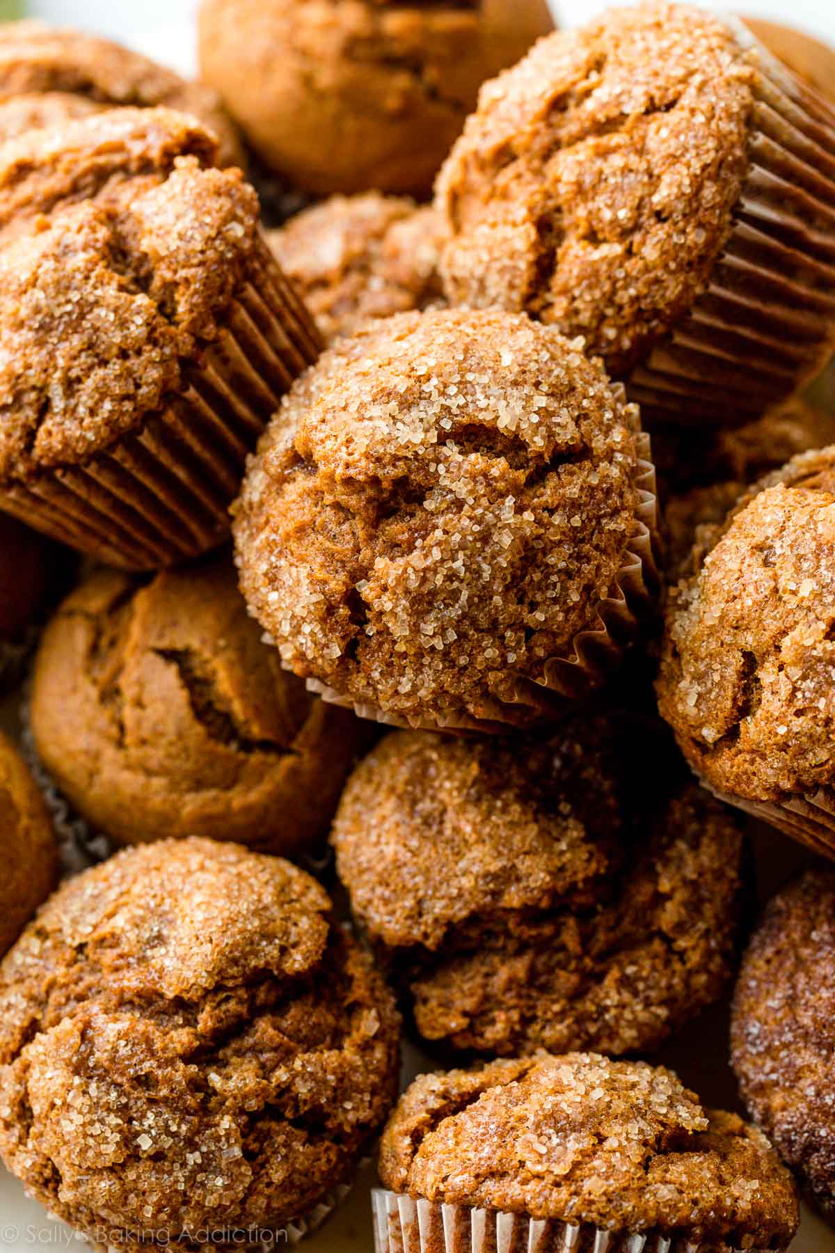 close-up photo of many pumpkin muffins topped with coarse sugar.