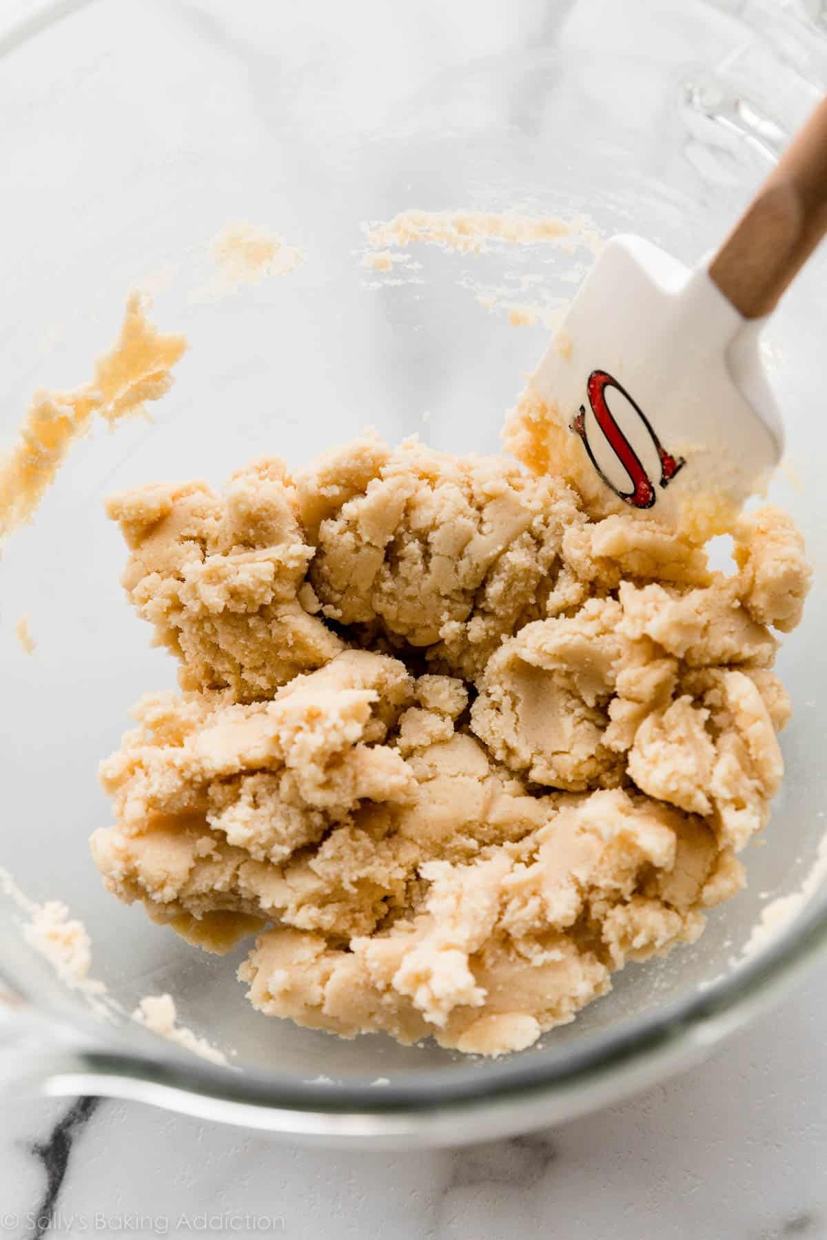 glass bowl of vanilla cookie dough with white spatula with letter S on it.