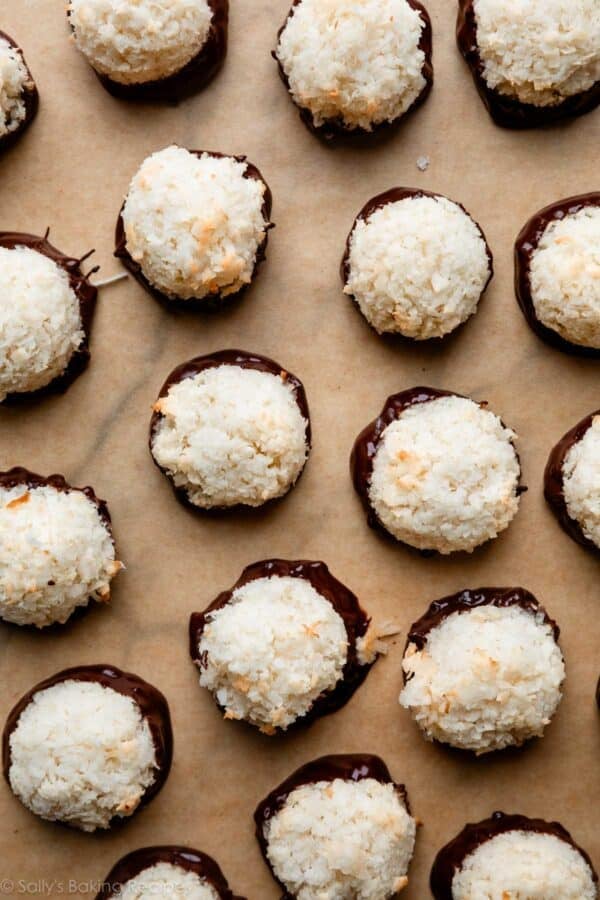 chocolate dipped coconut macaroons on brown parchment paper.