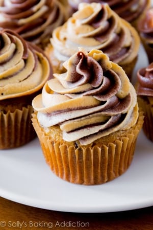 banana chocolate chip cupcakes topped with chocolate peanut butter swirl frosting on a white plate