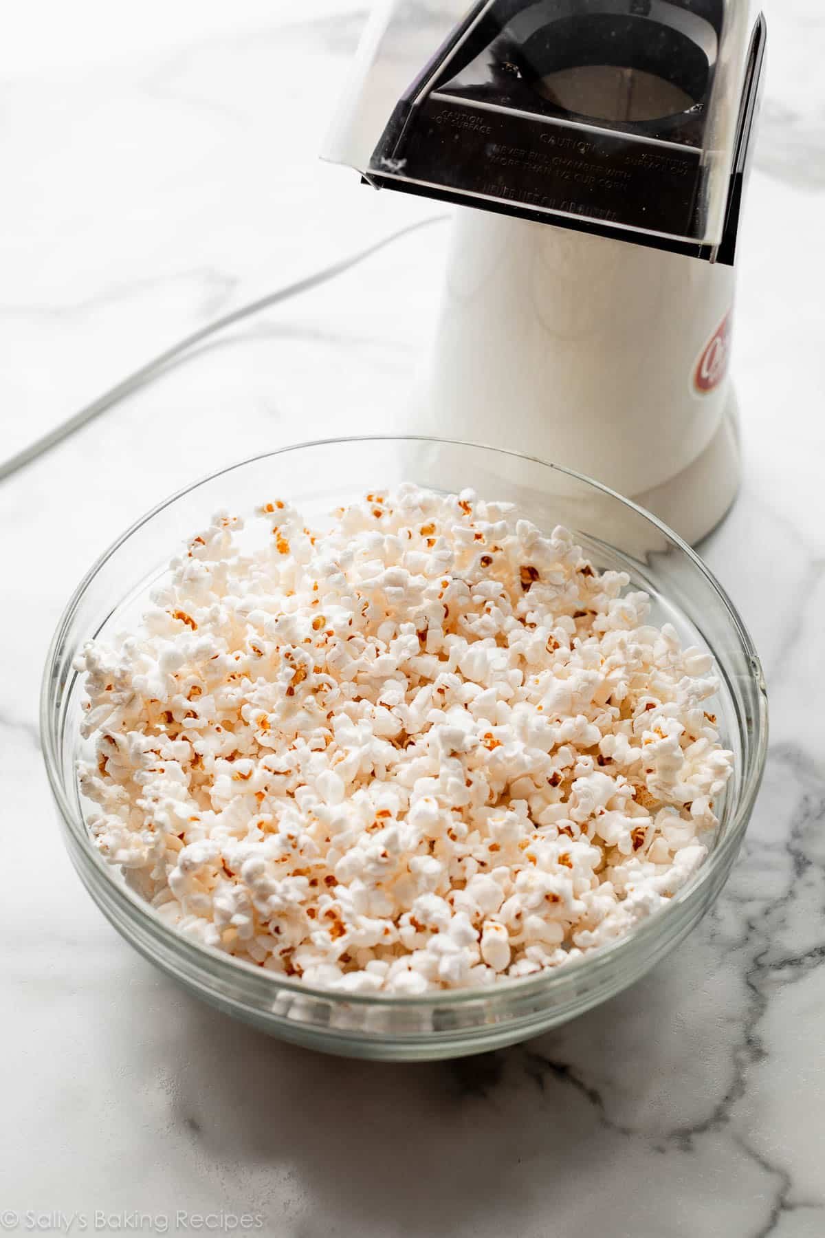 air-popped popcorn in bowl with popcorn making in background.