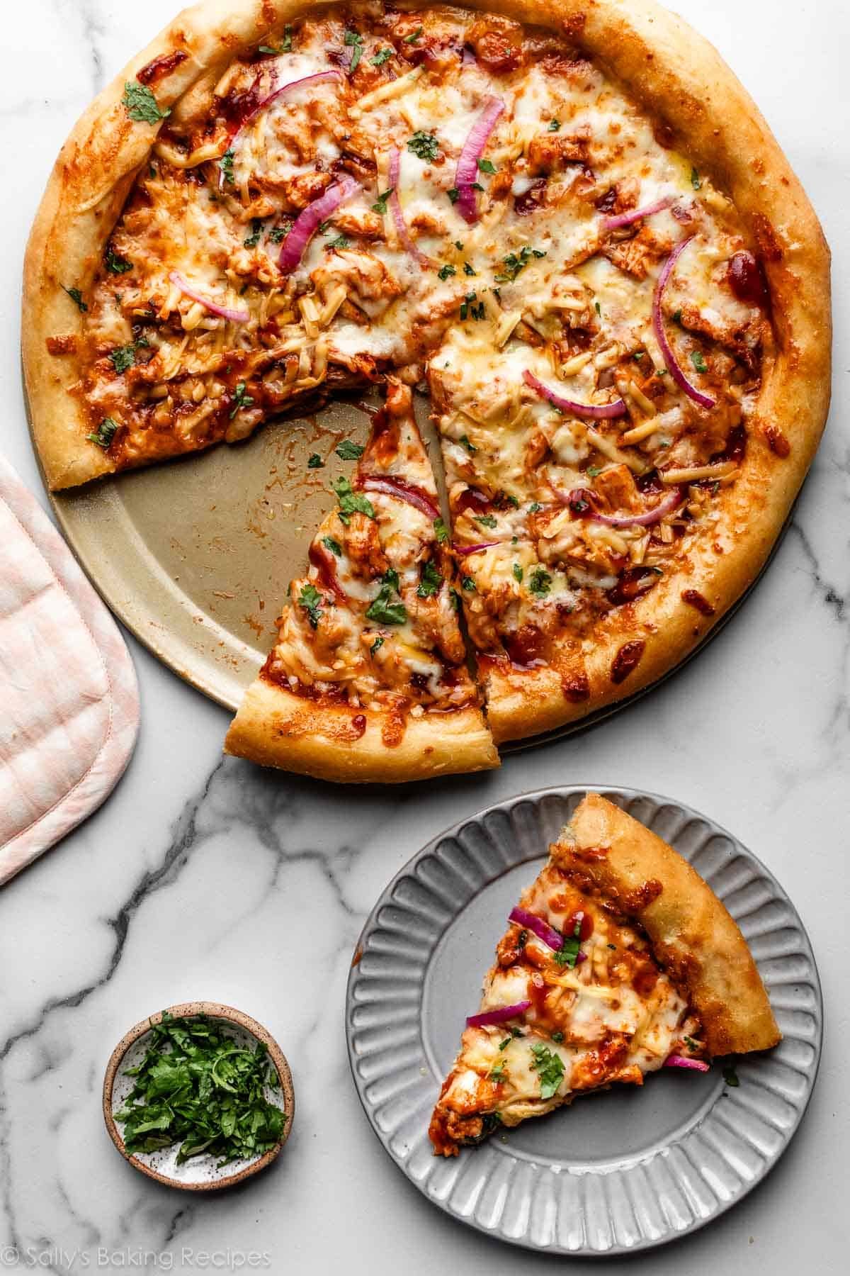 barbecue chicken pizza cut into two slices with one on a gray plate.