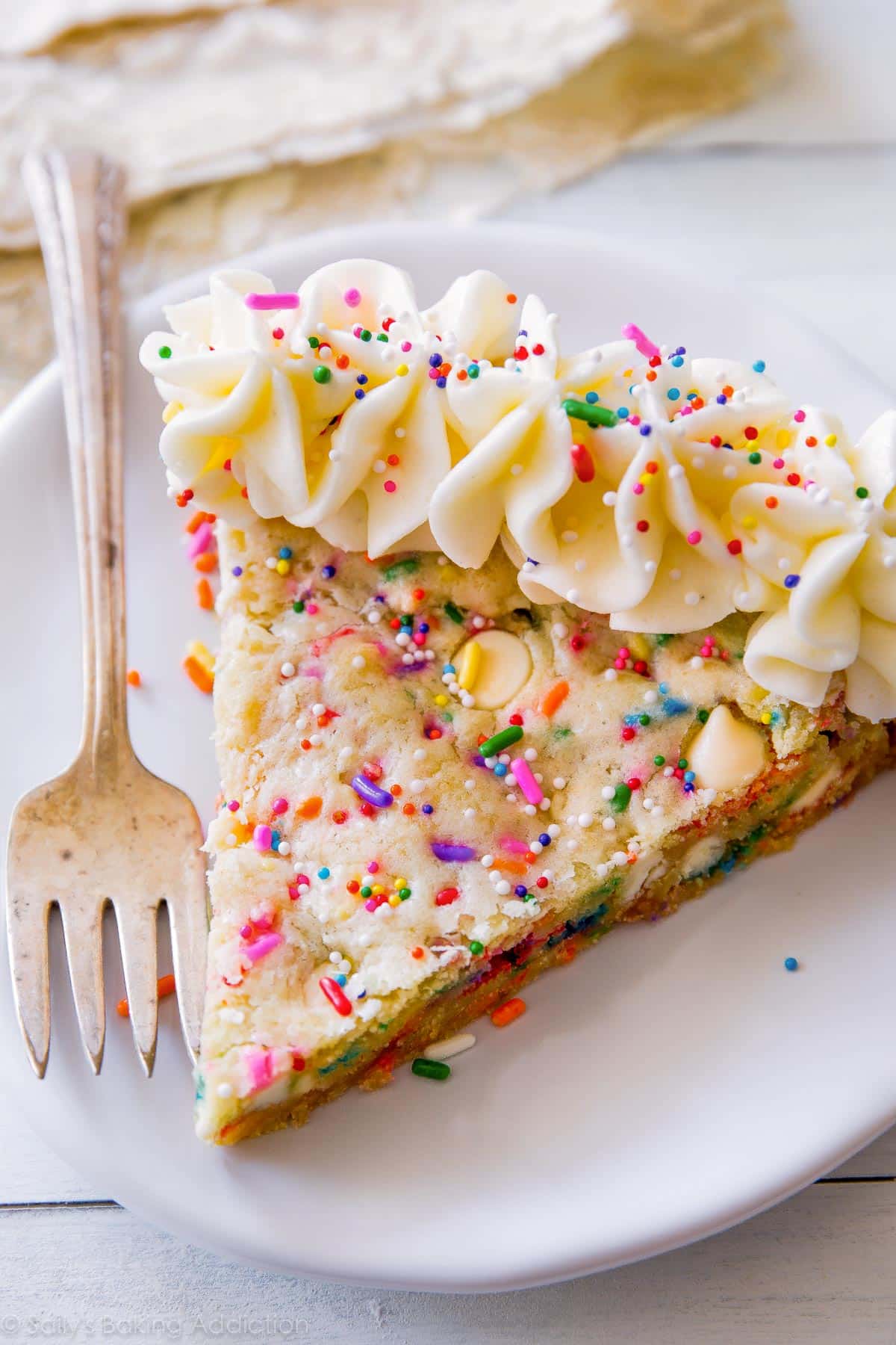 slice of funfetti sugar cookie cake on a white plate with a fork