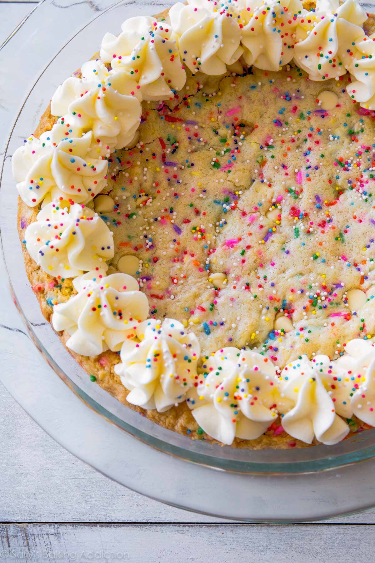 funfetti sugar cookie cake with piped frosting decorations and sprinkles in a glass baking dish