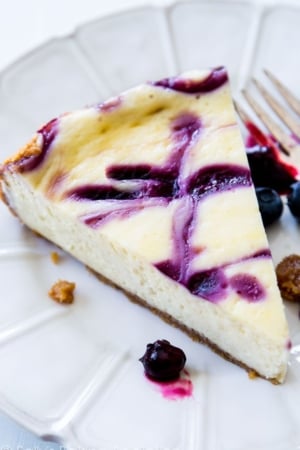 slice of blueberry swirl cheesecake on a white plate with a fork