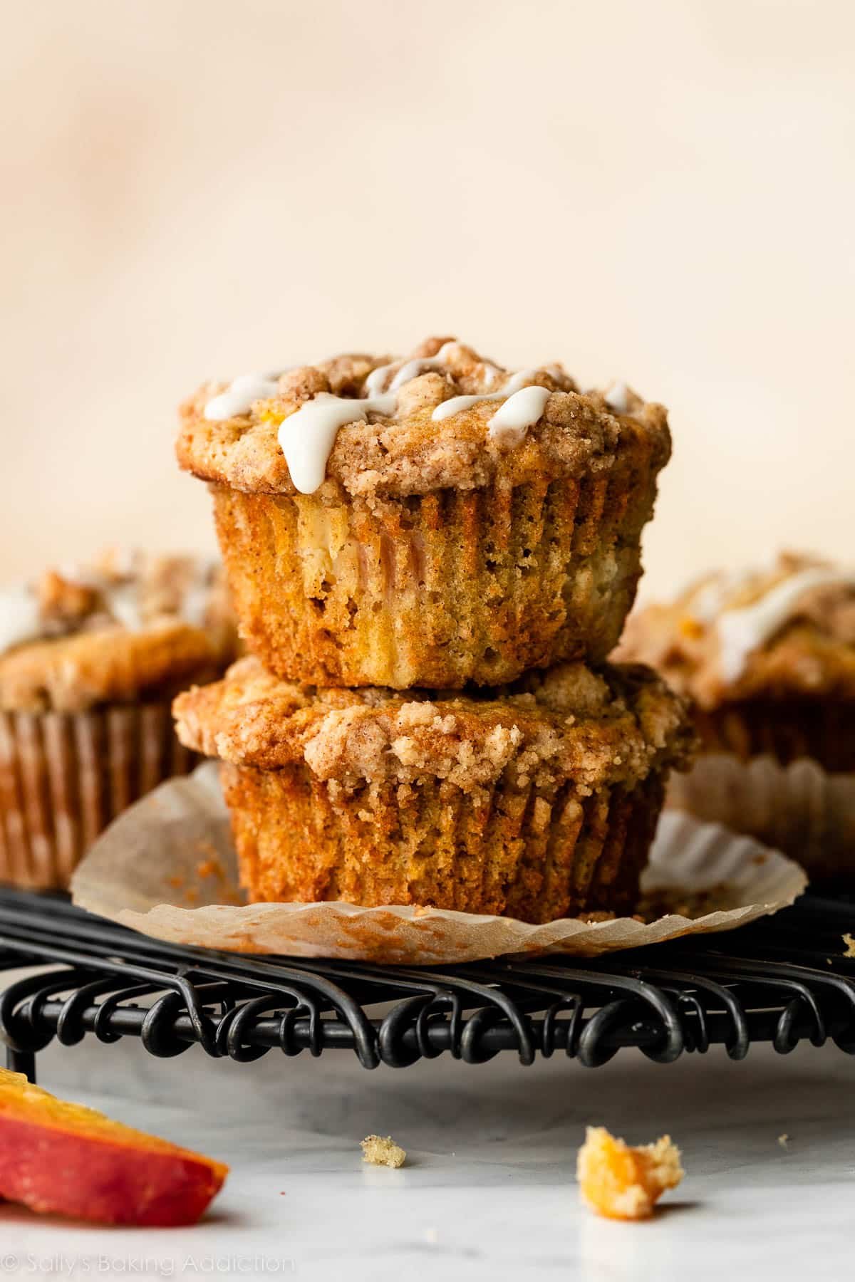 stack of 2 peach muffins on black cooling rack.