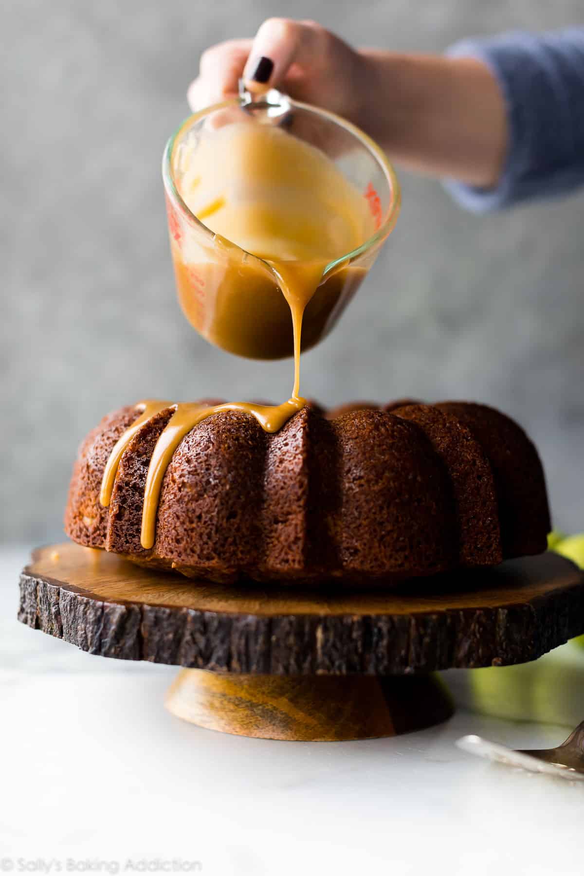 Pouring brown sugar glaze onto apple bundt cake