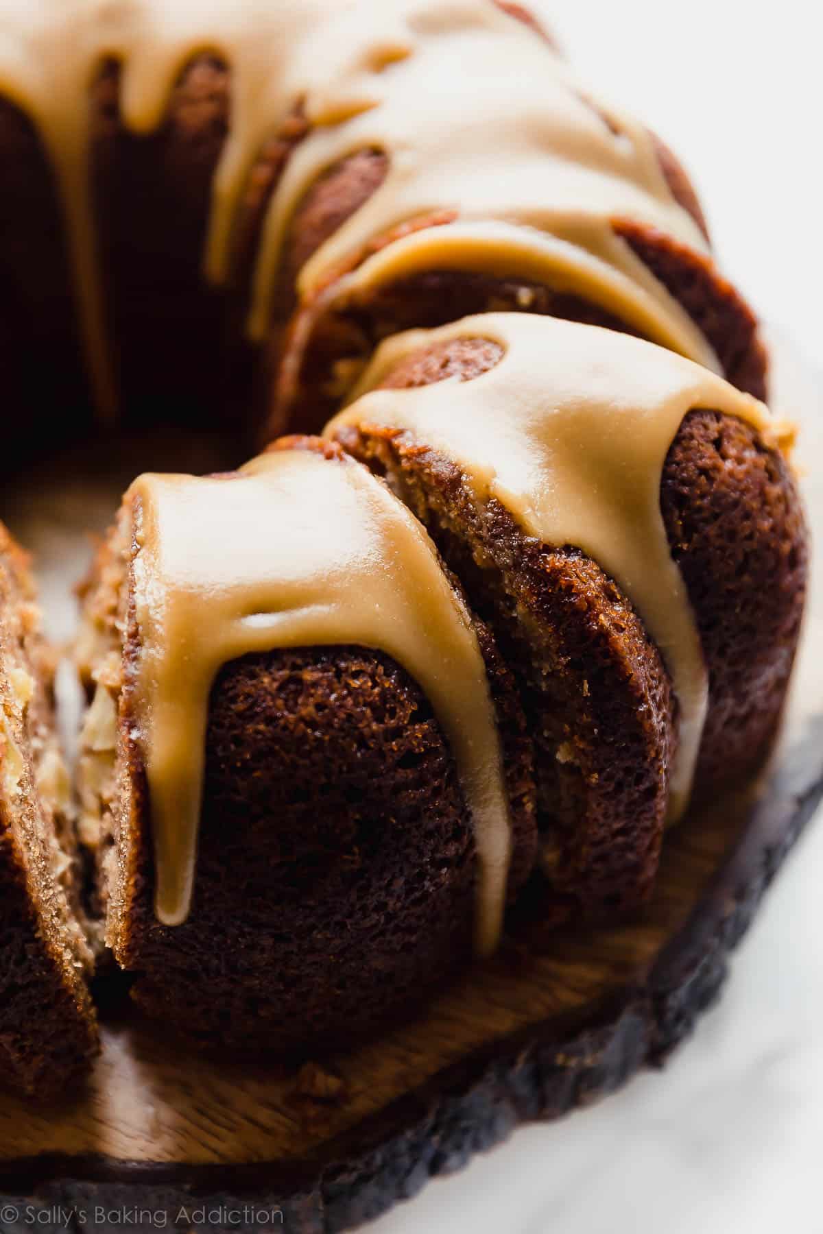 apple bundt cake cut into slices on a wood slice cake stand