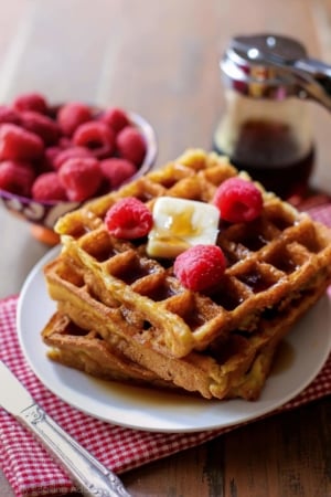 stack of buttermilk waffles with raspberries on a cream plate