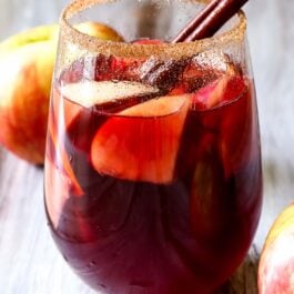 honeycrisp apple sangria with a cinnamon stick in a glass with the rim dipped in cinnamon sugar