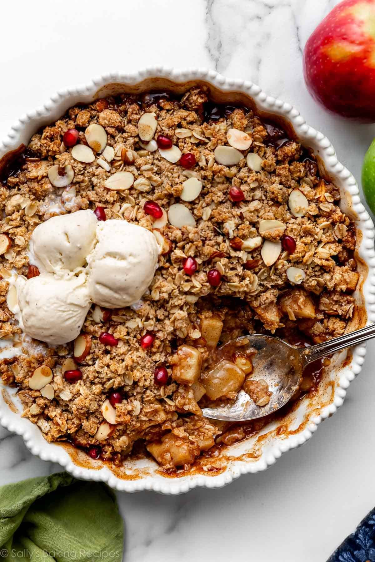 gluten free apple crisp with vanilla ice cream, almonds, and pomegranate seeds on top.