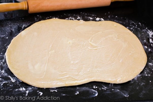 deep dish pizza dough rolled out with butter spread on top