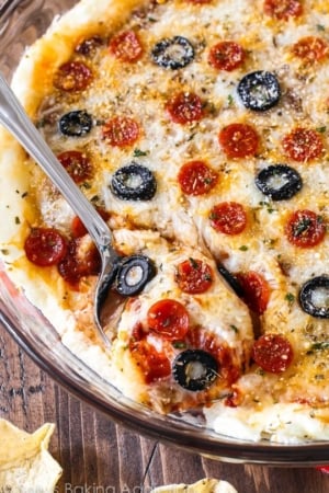 overhead image of pepperoni pizza dip in a glass baking dish with a spoon