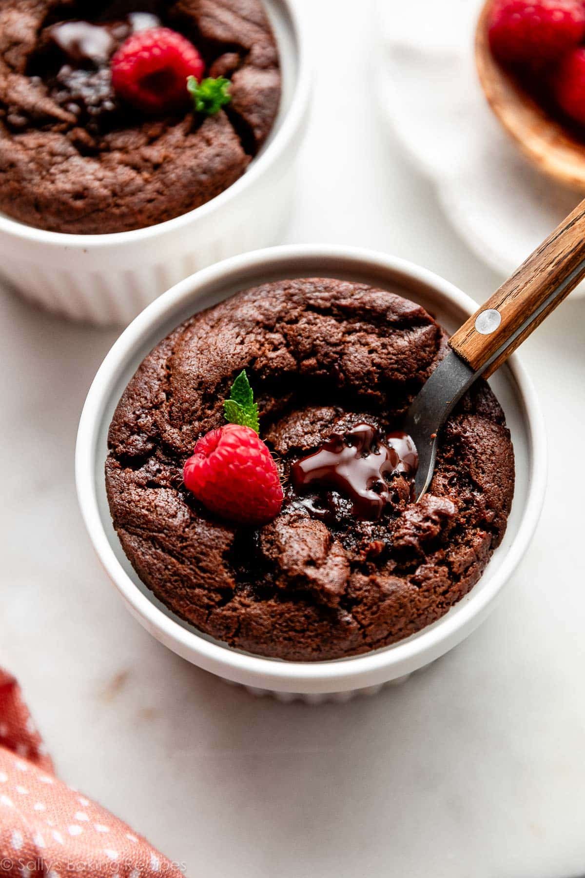 chocolate fudge cake in ramekin with raspberry on top.