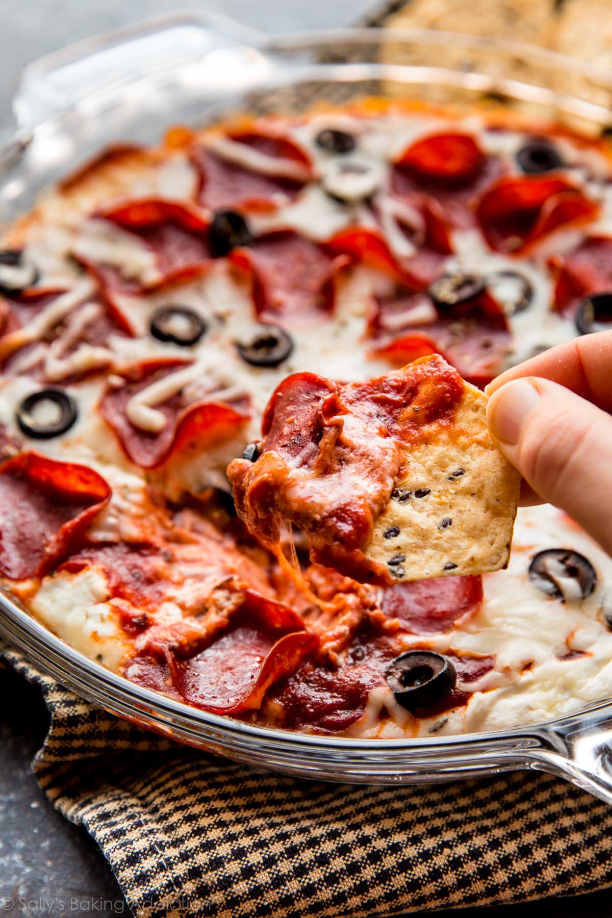 dipping a chip into pepperoni pizza dip