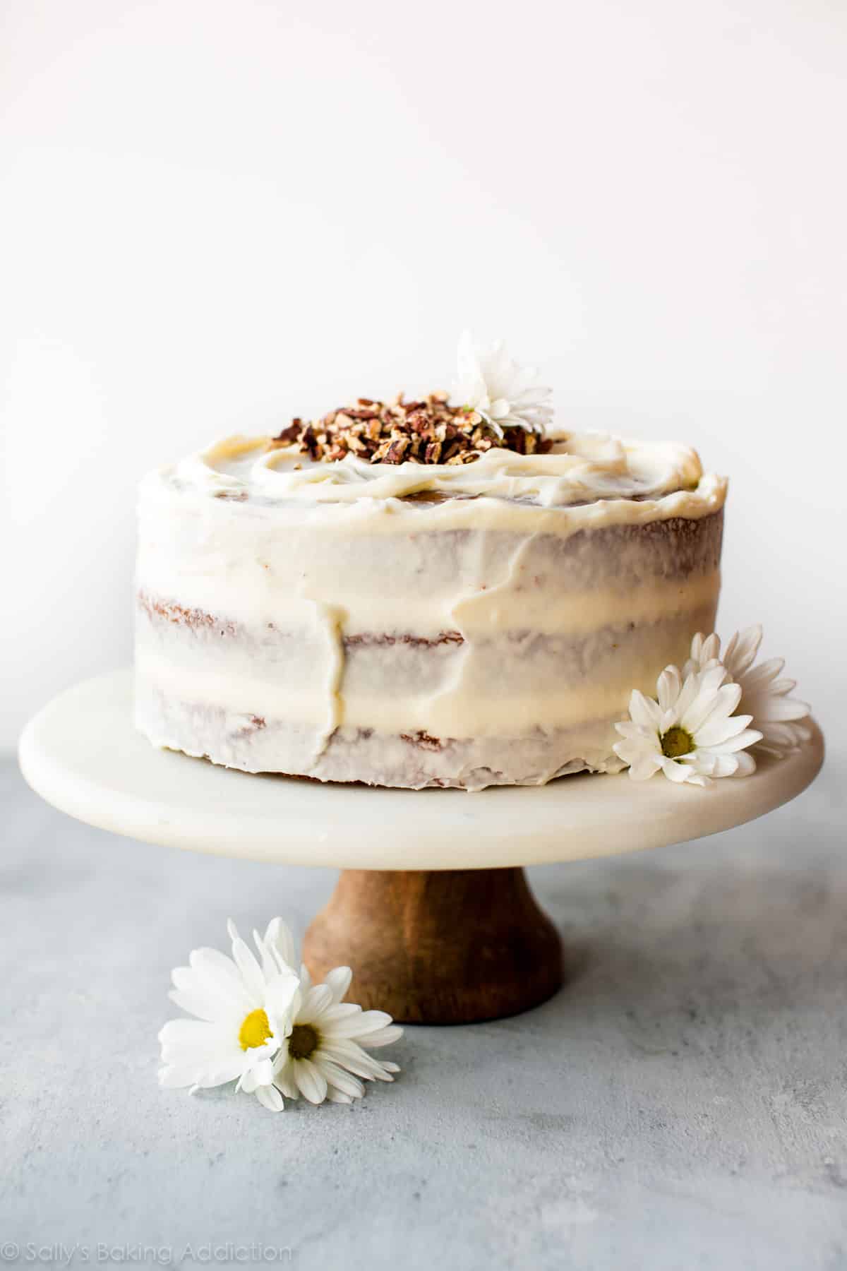 Carrot cake with cream cheese frosting on marble and wood cake stand