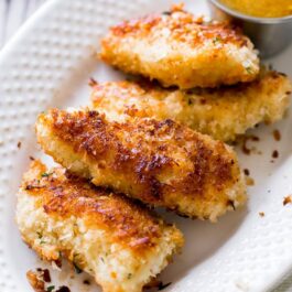 coconut chicken on a white plate with dipping sauce