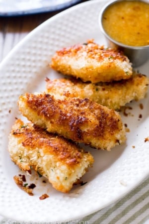 coconut chicken on a white plate with dipping sauce