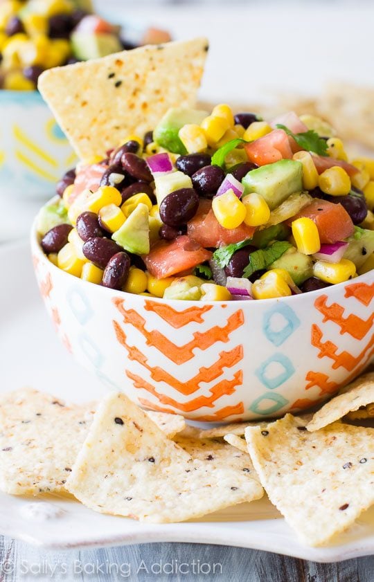 avocado corn salsa in a colorful bowl with chips