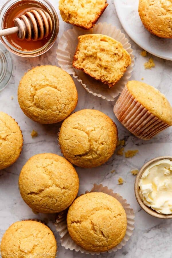 overhead photo of cornbread muffins with one cut in half shown with honey next to it.