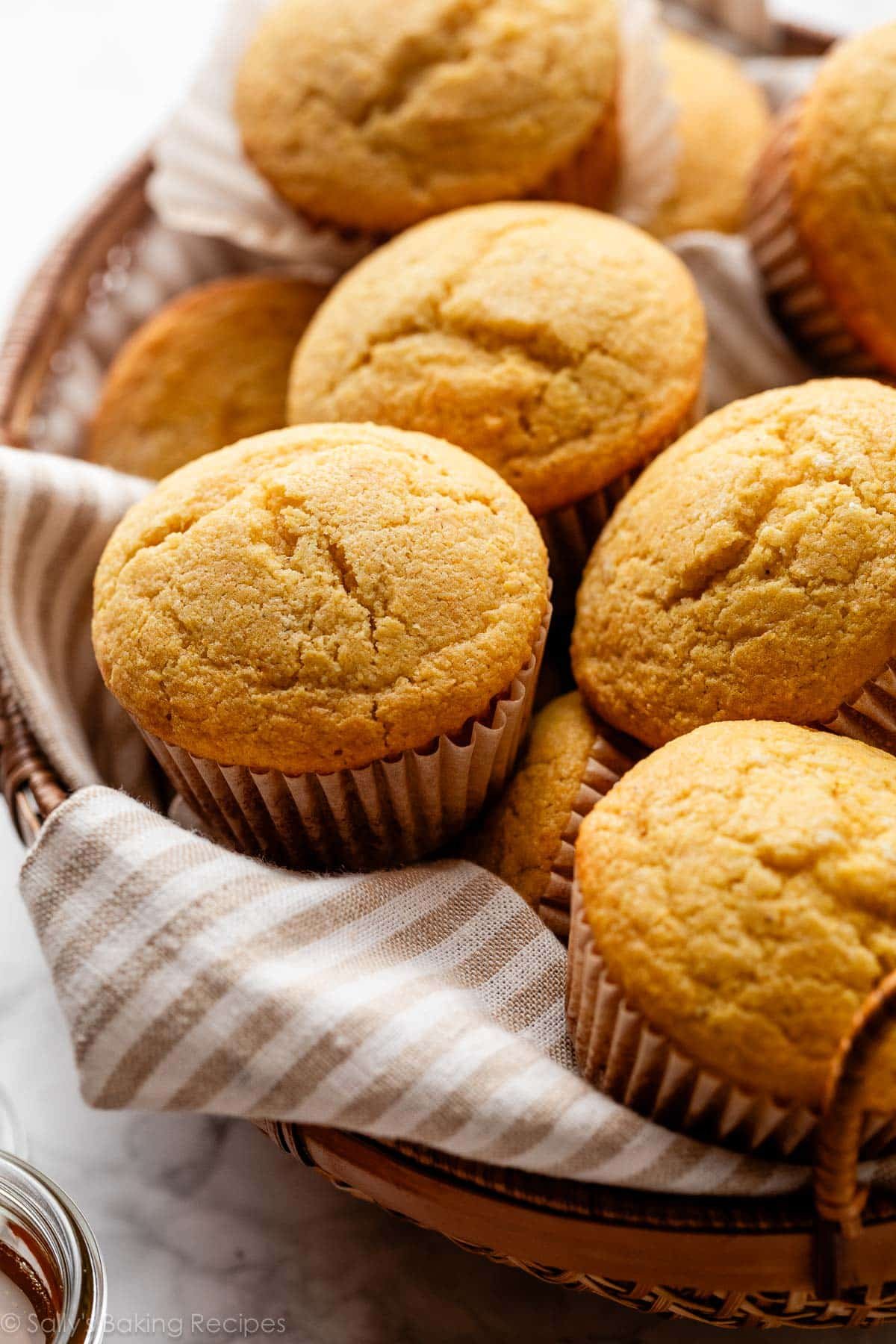 basket of cornbread muffins with beige striped linen.