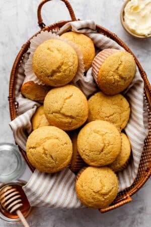 basket of cornbread muffins with beige striped linen.