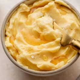 homemade honey butter in bowl with flaky sea salt on top.