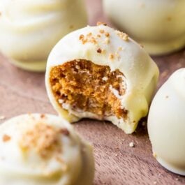 pumpkin spice truffles coated in white chocolate with a bite taken out of one showing the inside