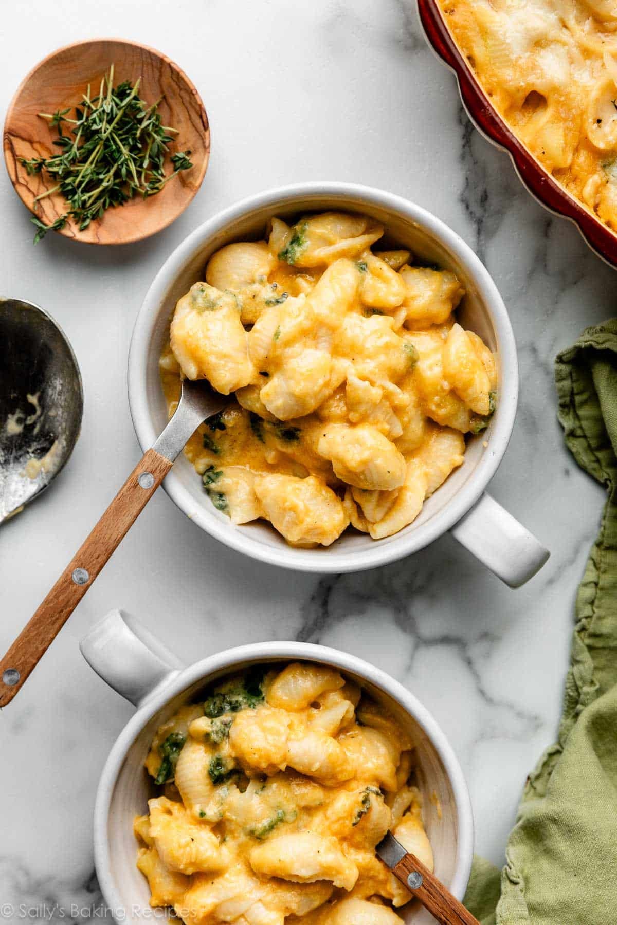 two bowls of butternut squash macaroni & cheese with wooden and metal forks in them.