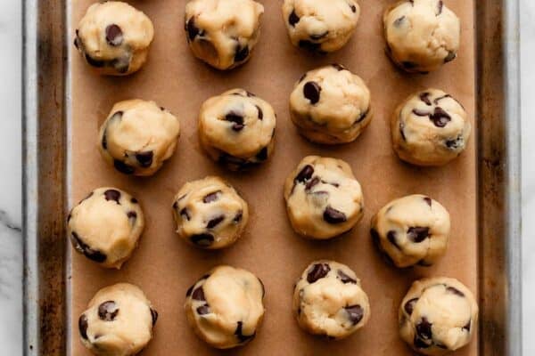 chocolate chip cookie dough balls on parchment paper-lined baking sheet.