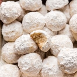 snowball cookies coated in powdered sugar in baking dish.