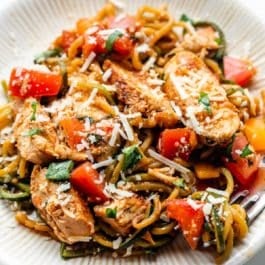 bruschetta chicken and zucchini noodles with parmesan cheese sprinkled on top on plate.