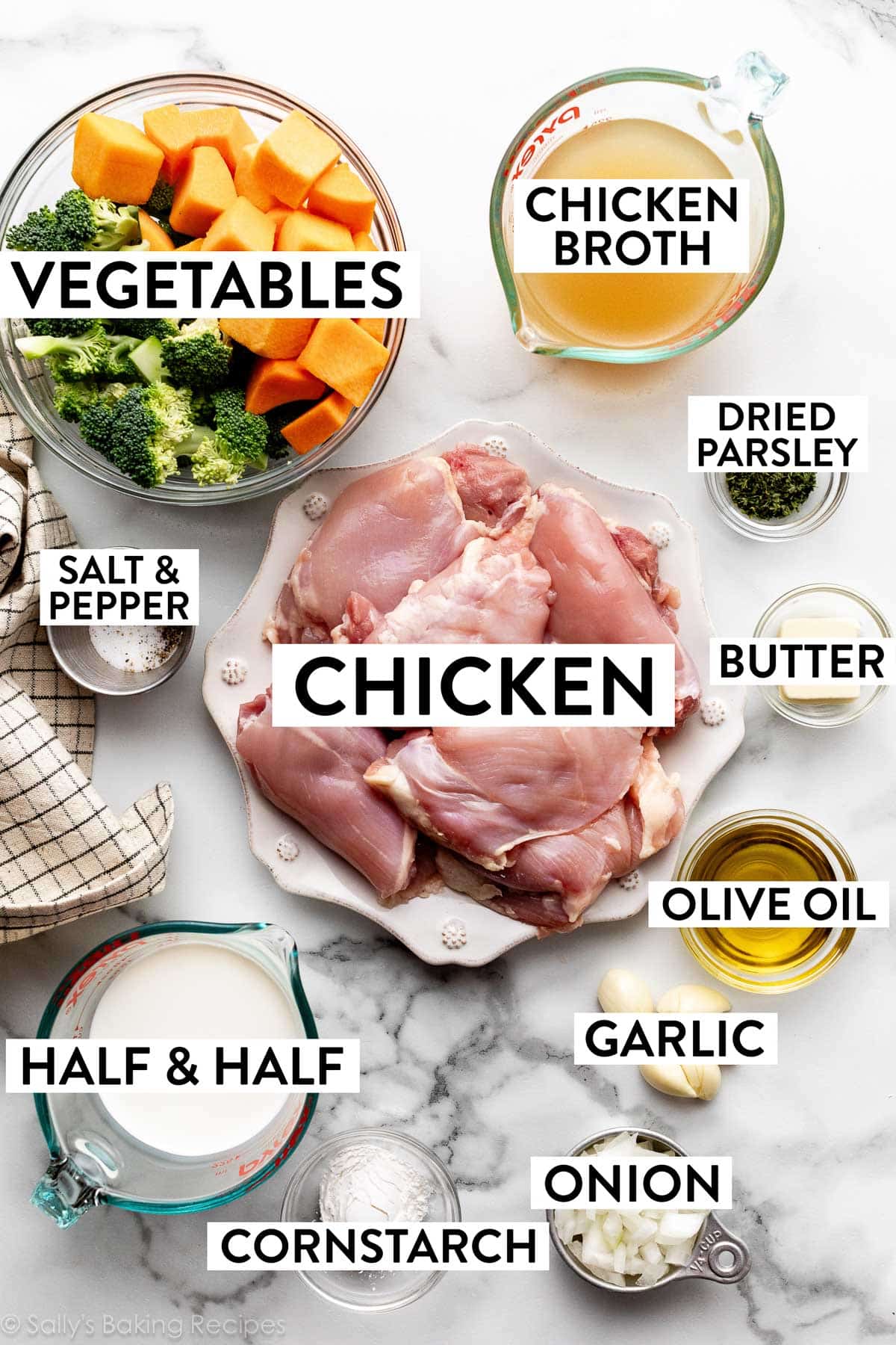 ingredients on counter including a bowl of broccoli and butternut squash, chicken thighs on a plate, measured chicken broth, garlic cloves, cornstarch, chopped onion, and dried parsley.