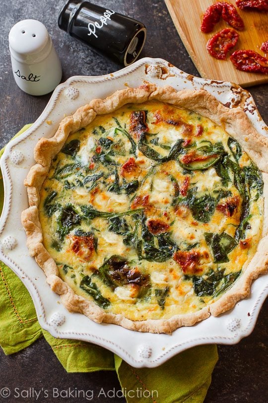 overhead image of goat cheese spinach sun-dried tomato quiche in a white pie dish