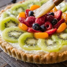 brushing fruit glaze onto fresh fruit tart