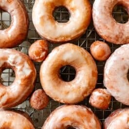 glazed doughnuts on wire cooling rack on top of baking sheet.