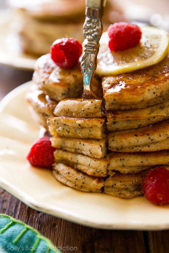 stack of lemon poppy seed pancakes with maple syrup on a cream plate