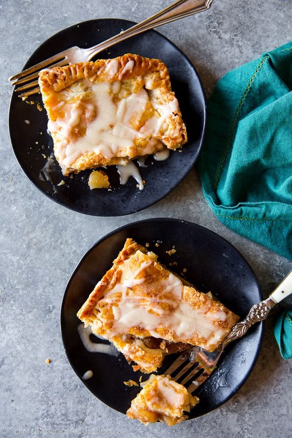 overhead image of slices of apple slab pie on black plates with forks