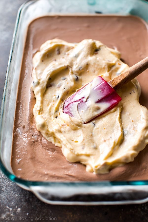 spreading softened peanut butter cup ice cream onto chocolate ice cream layer in a glass baking dish