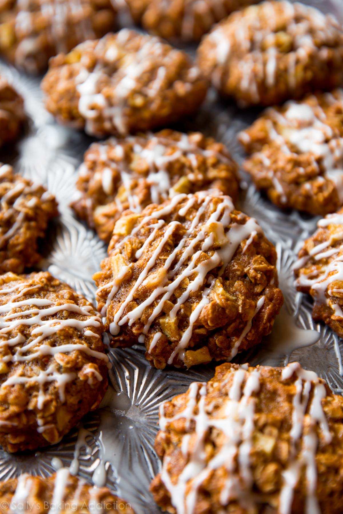 apple cinnamon oatmeal cookies with maple icing on a baking sheet