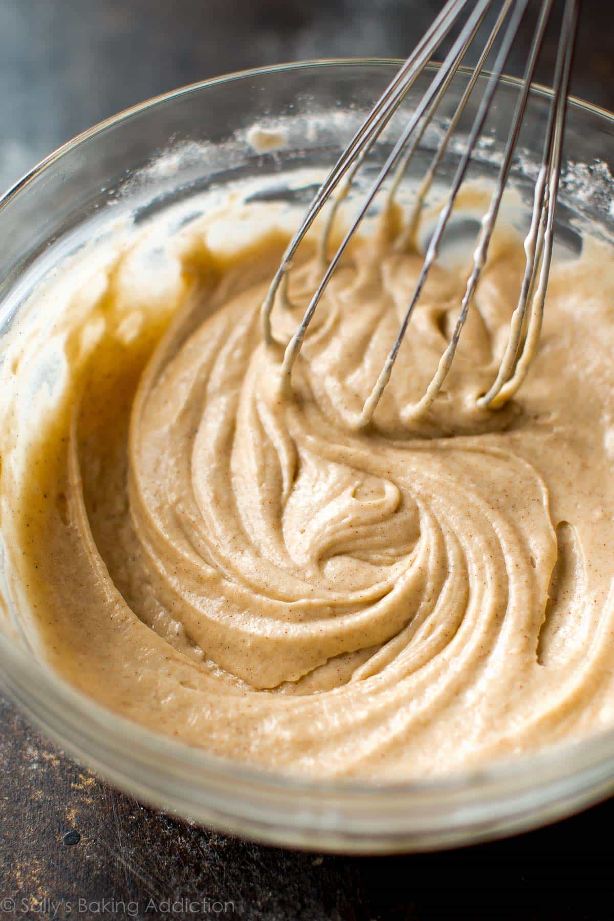 chai spice donut batter in a glass bowl with a metal whisk