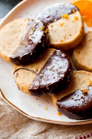 orange slice and bake cookies with half of each cookie dipped in dark chocolate on a white plate