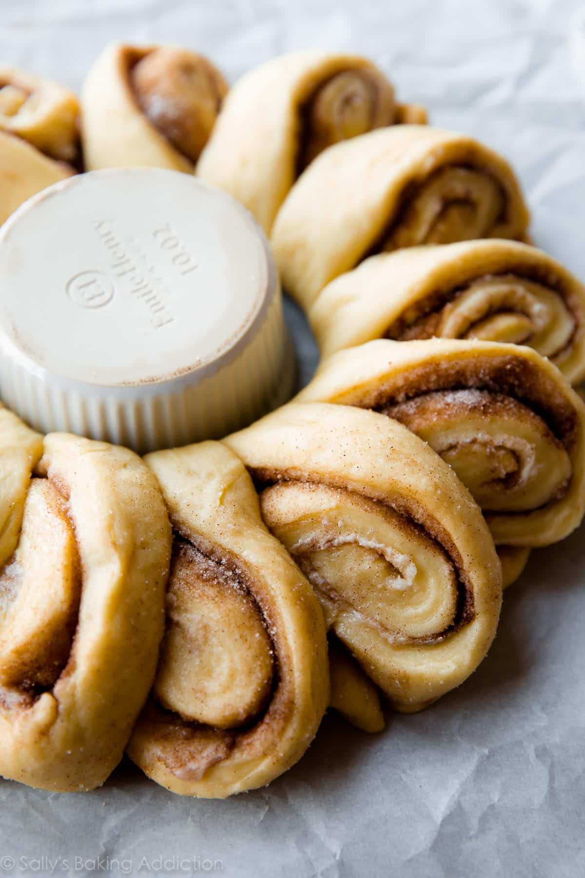 cinnamon roll wreath around a white ramekin before baking